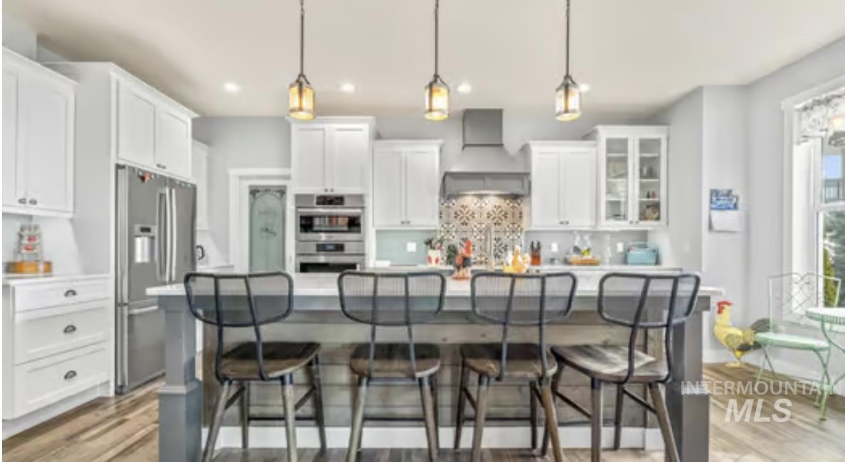 16353 Brunello Court Caldwell, ID 83607 - Photo 9 of 34 Kitchen featuring stainless steel appliances, light countertops, white cabinets, an island with sink, and a breakfast bar