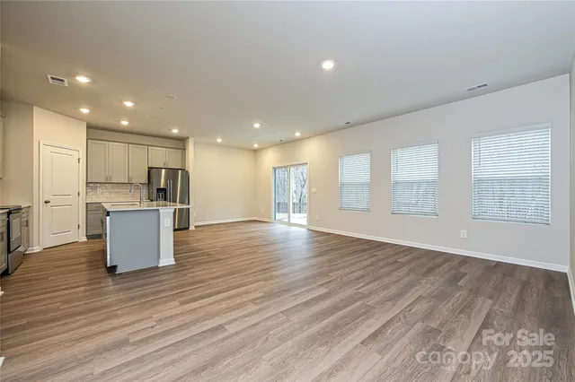 a view of kitchen with kitchen island wooden floors and stainless steel appliances