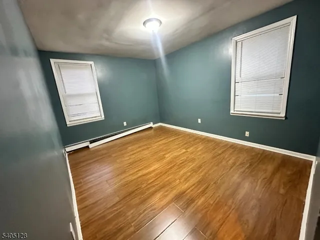 a view of empty room with window and wooden floor
