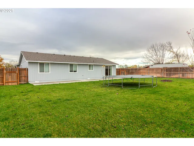 a view of a backyard with table and chairs and wooden fence