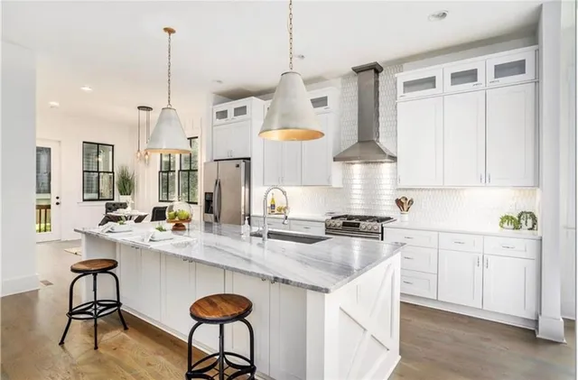 a kitchen with stainless steel appliances granite countertop a sink a stove and a wooden floors