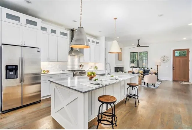 a kitchen with stainless steel appliances granite countertop a sink a stove a refrigerator and island with wooden floor