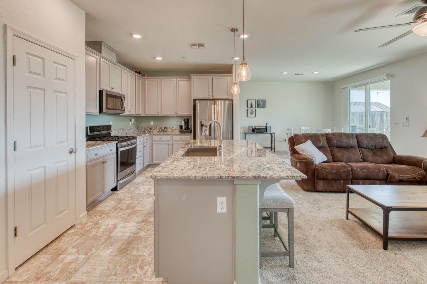 3606 Morro Rock Place Madera, CA 93637 - Photo 12 of 46 a kitchen with stainless steel appliances granite countertop a stove top oven a sink dishwasher a refrigerator and white cabinets with wooden floor