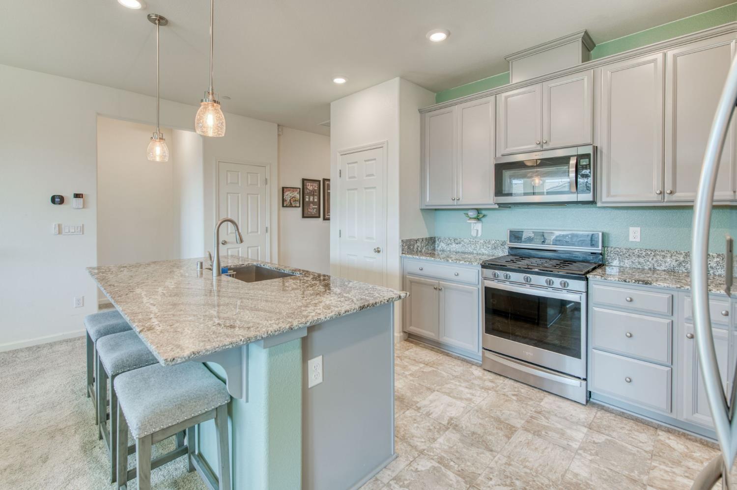 3606 Morro Rock Place Madera, CA 93637 - Photo 16 of 46 a kitchen with kitchen island granite countertop a sink cabinets and stainless steel appliances