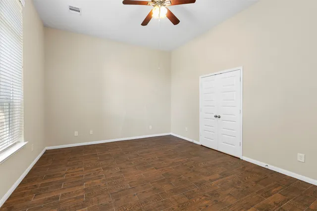 an empty room with a window and a ceiling fan