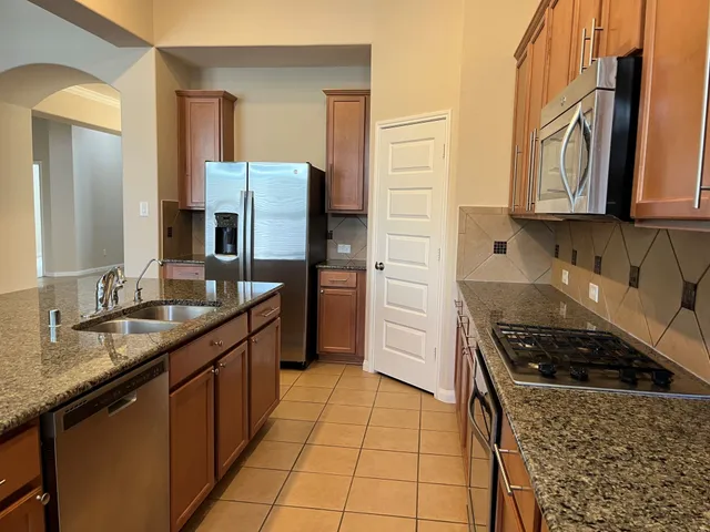 a kitchen with stainless steel appliances granite countertop a sink stove and refrigerator
