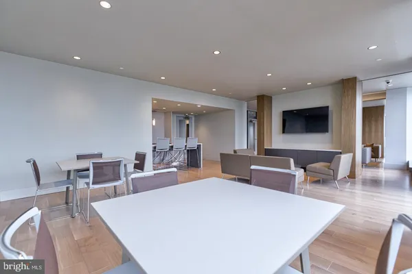 a large white dining hall with stainless steel appliances a dining table and chairs with kitchen island