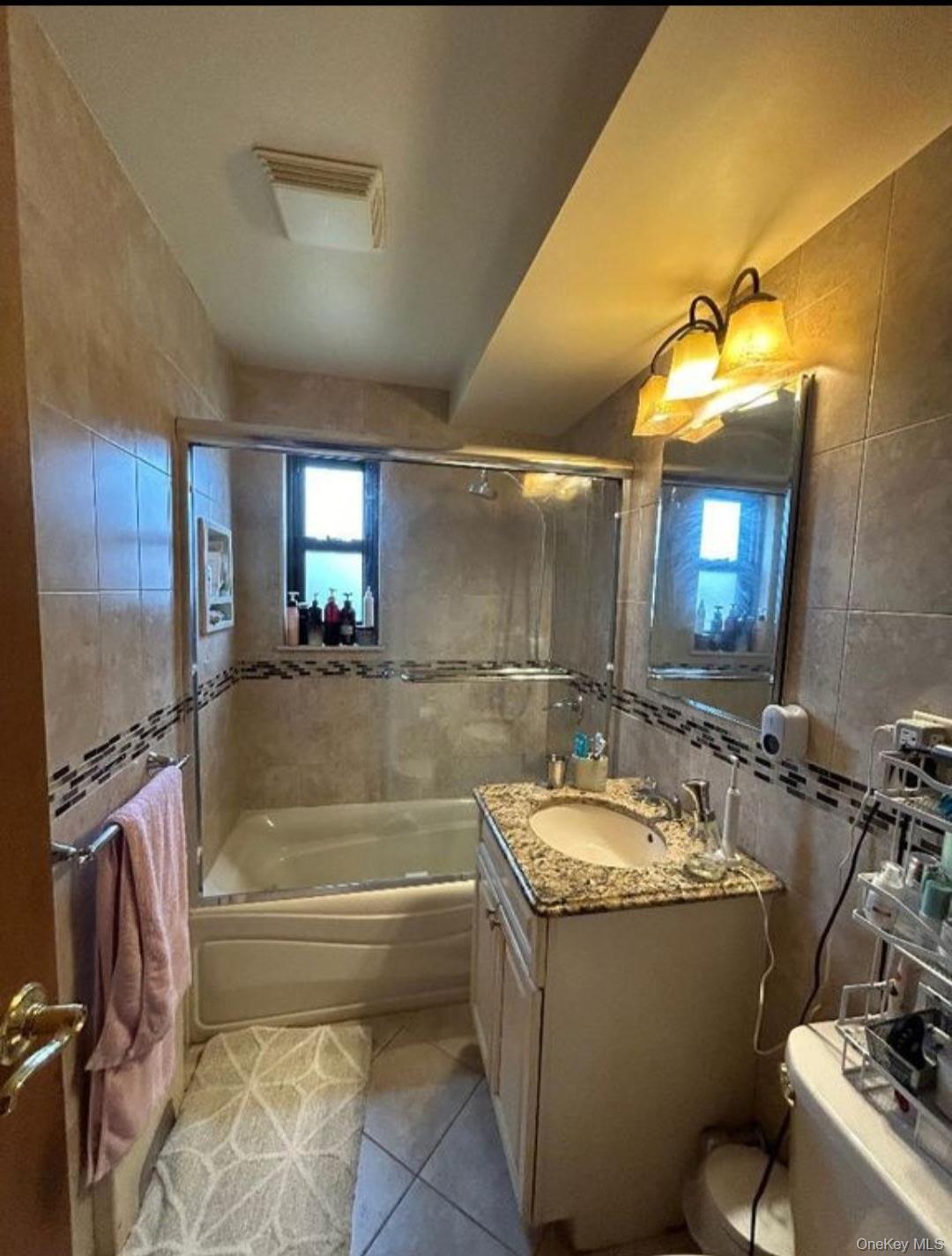 199-05 21st Avenue, Unit 1 Queens, NY 11357 - Photo 12 of 13 a bathroom with a tub a sink and mirror