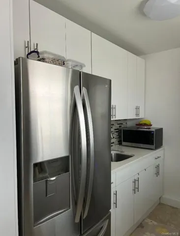 a kitchen with metallic refrigerator and white cabinets