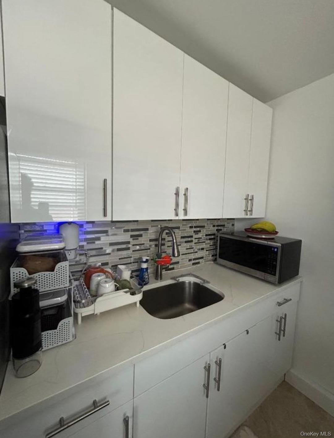 199-05 21st Avenue, Unit 1 Queens, NY 11357 - Photo 10 of 13 a kitchen with a sink a stove and cabinets