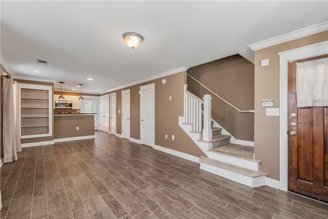 a view of an empty room with wooden floor and stairs