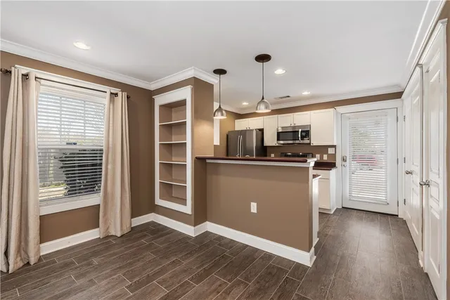 a kitchen with stainless steel appliances granite countertop a refrigerator a oven a sink with white cabinets and wooden floor