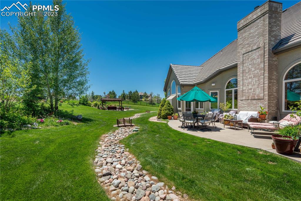 8760 Ridgepointe Drive Castle Pines, CO 80108 - Photo 44 of 50 a view of a house with backyard sitting area and garden