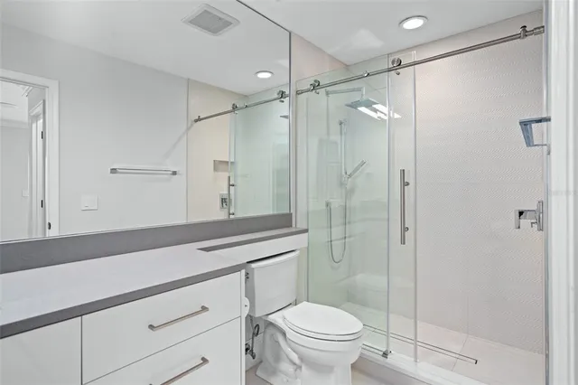 a spacious bathroom with a granite countertop sink a toilet a shower and a mirror