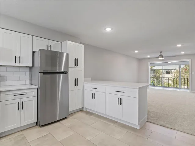 a kitchen with granite countertop white cabinets and refrigerator