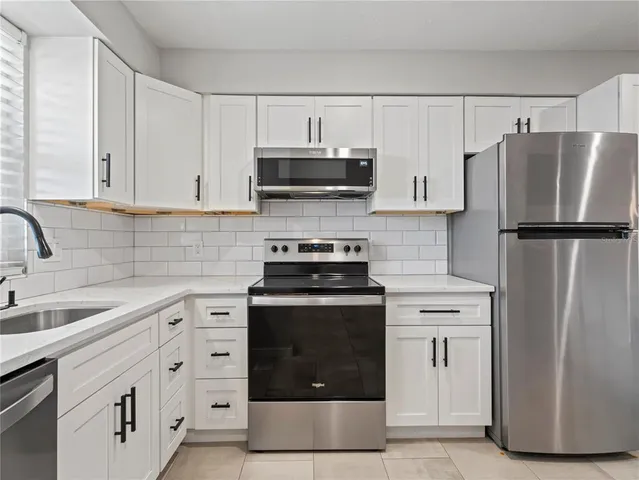 a kitchen with white cabinets and stainless steel appliances