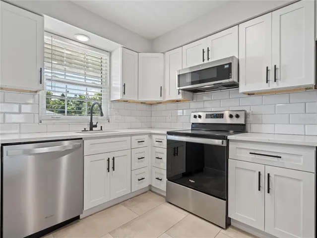 a kitchen with white cabinets stainless steel appliances and window