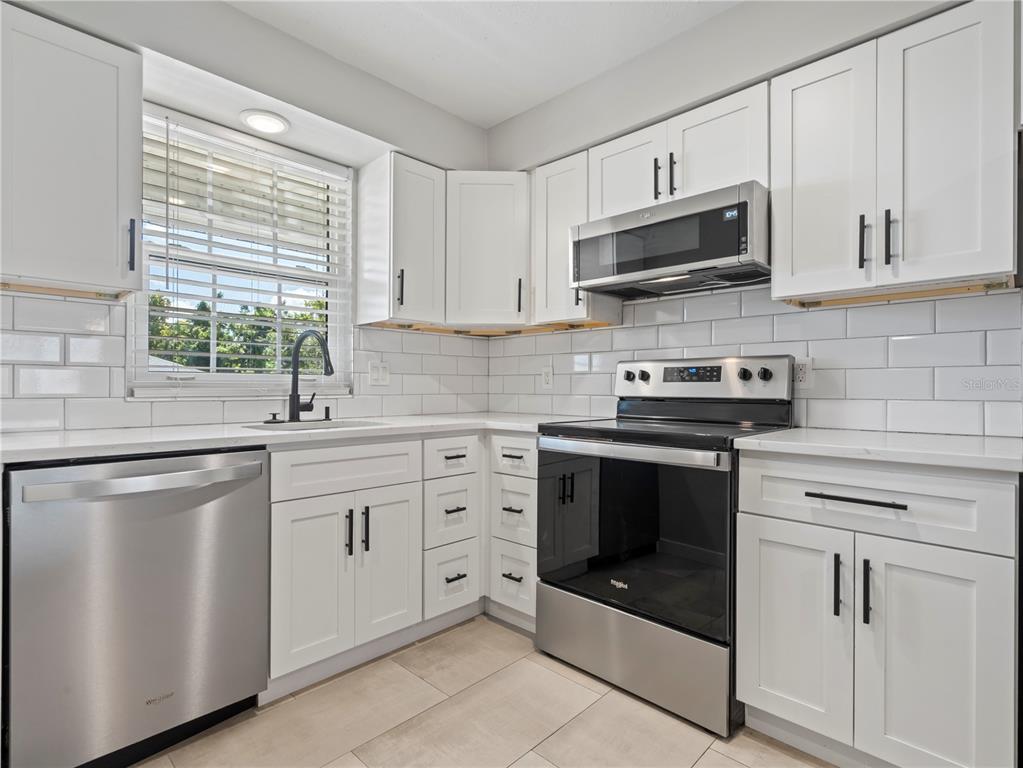 1250 South Denning Drive, Unit 213 Winter Park, FL 32789 - Photo 7 of 20 a kitchen with white cabinets stainless steel appliances and window