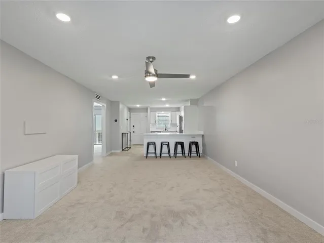 a view of an empty room with kitchen and a window
