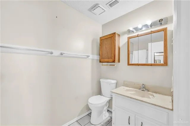 a bathroom with a granite countertop sink vanity mirror and toilet