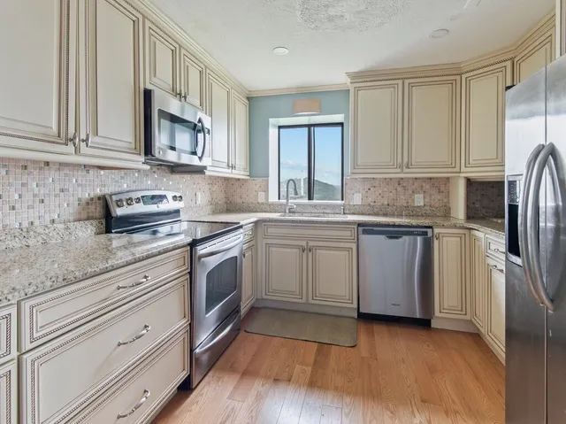 a kitchen with stainless steel appliances granite countertop a sink a stove a refrigerator and cabinets