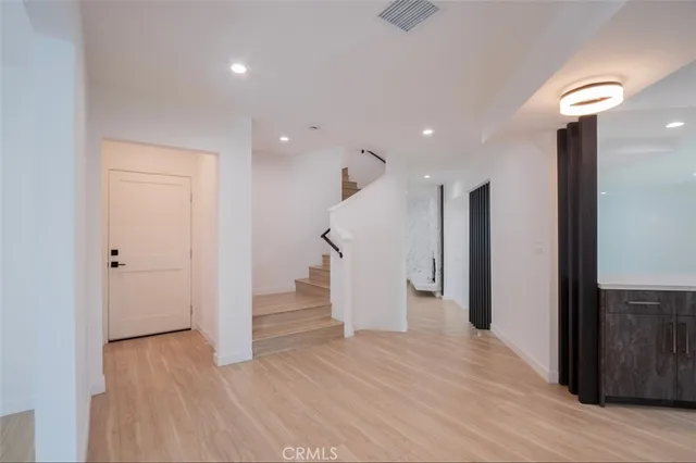 a view of an empty room with wooden floor and staircase