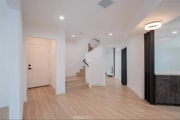 a view of an empty room with wooden floor and staircase