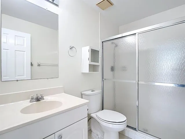 a view of an empty room with wooden floor and a ceiling fan