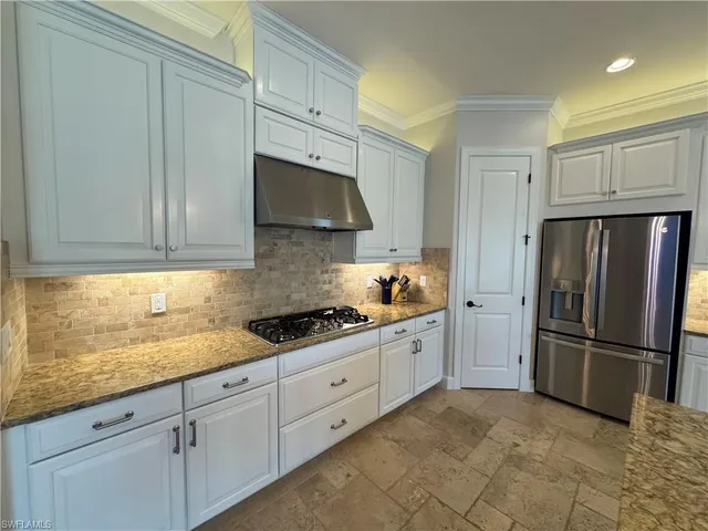 a kitchen with granite countertop a refrigerator stove and sink