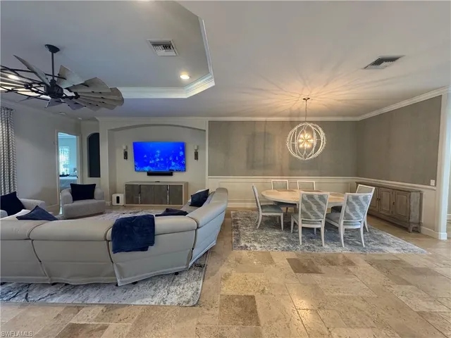 a living room with furniture a chandelier and a flat screen tv