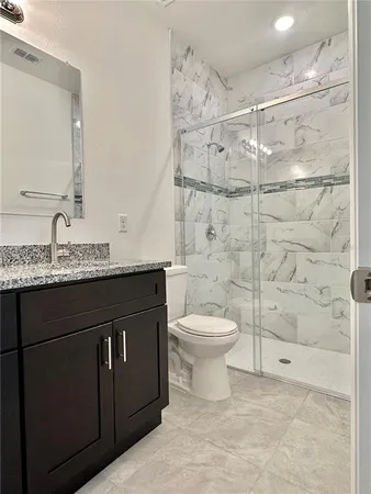 a bathroom with a granite countertop sink toilet and shower