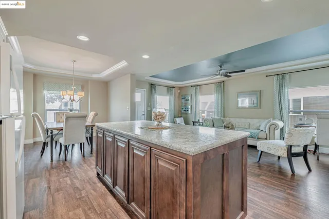 a dining hall with stainless steel appliances granite countertop a table chairs and a wooden floors