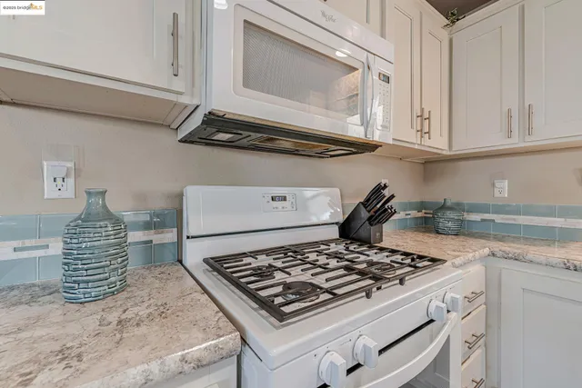 a kitchen with white cabinets and appliances