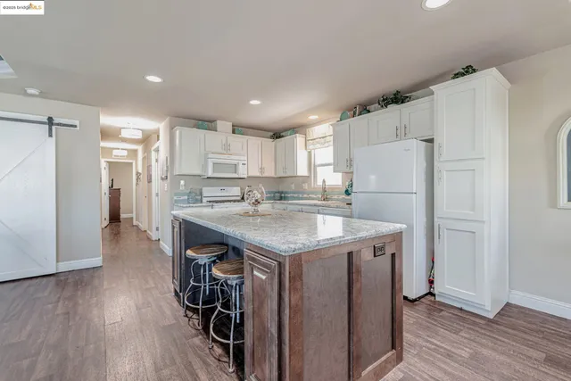 a kitchen with a refrigerator a sink and wooden floor