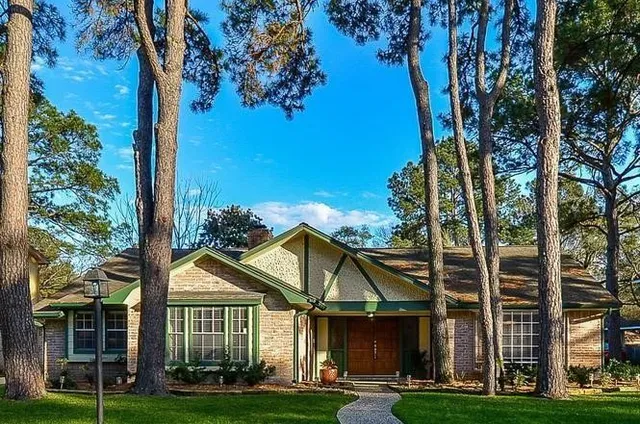 a view of a white house next to a yard with big trees
