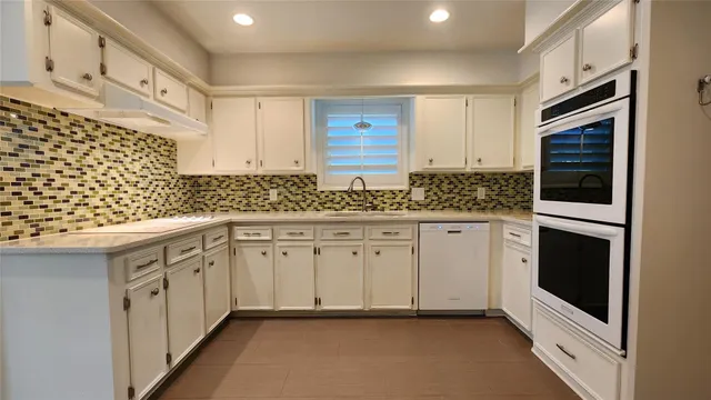 a kitchen with granite countertop white cabinets and white appliances