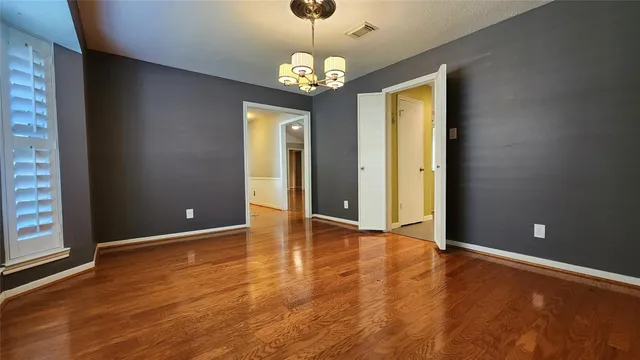 a view of an empty room with window and wooden floor