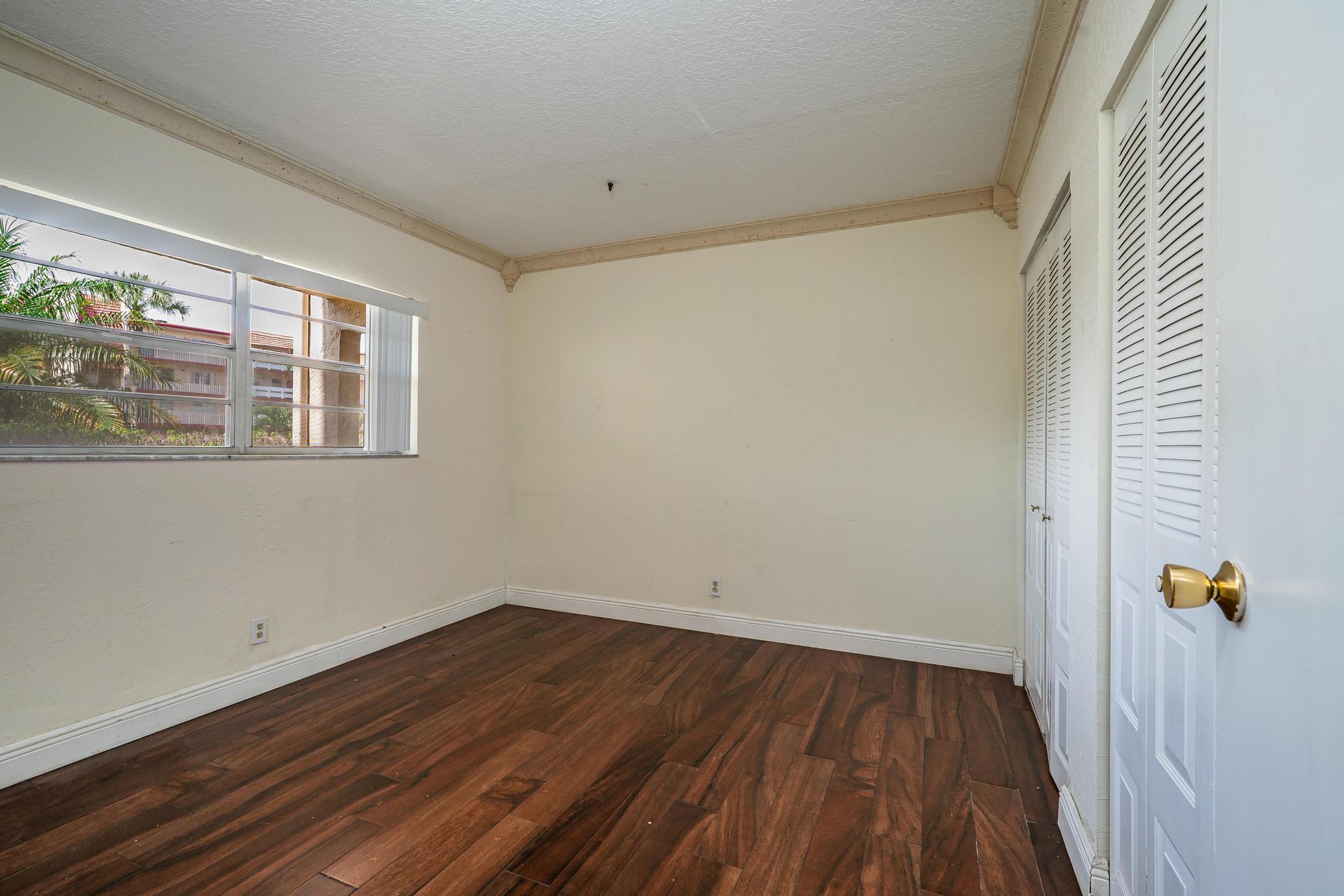 1010 Country Club Drive, Unit 108 Margate, FL 33063 - Photo 4 of 19 a view of an empty room with wooden floor and a window