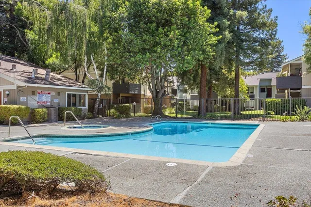 a view of swimming pool with outdoor seating and trees in the background