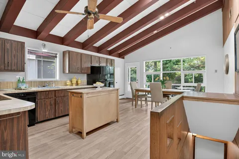 a kitchen with counter space wooden floor dining table and stainless steel appliances