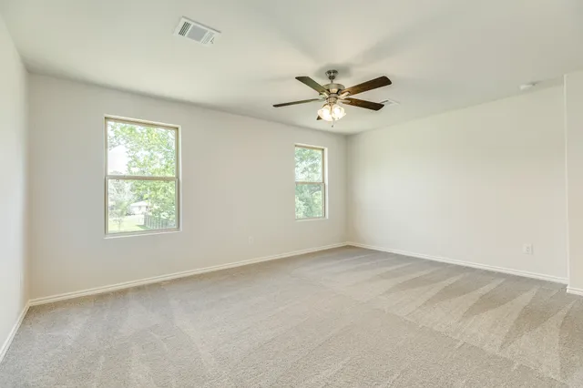 an empty room with windows and ceiling fan