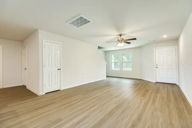 a view of an empty room with window and wooden floor