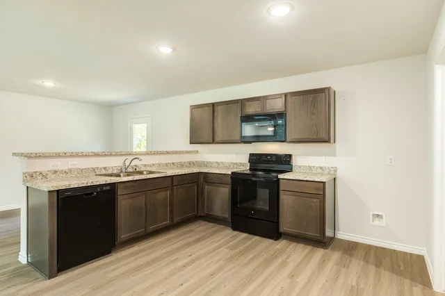 a kitchen with stainless steel appliances granite countertop a stove a sink and a microwave