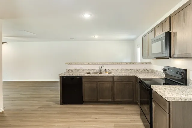 a kitchen with stainless steel appliances granite countertop a sink and dishwasher a stove top oven with wooden floor