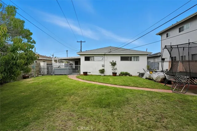 a view of a white house with a big yard potted plants and large tree