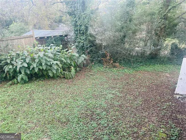 a view of a yard with plants and large trees