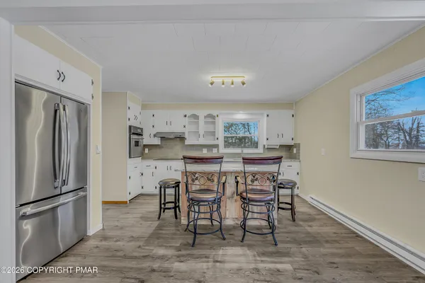 a kitchen with stainless steel appliances a refrigerator a stove a dining table and chairs