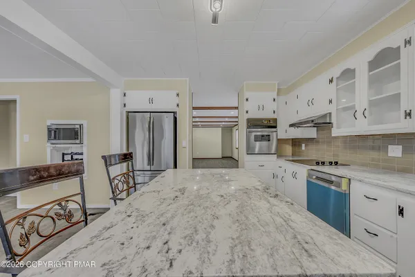 a kitchen with stainless steel appliances granite countertop a stove top oven a sink a refrigerator and white cabinets
