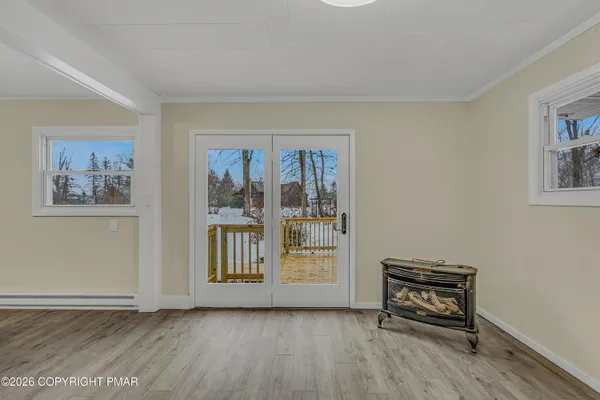 a view of an empty room with window and wooden floor