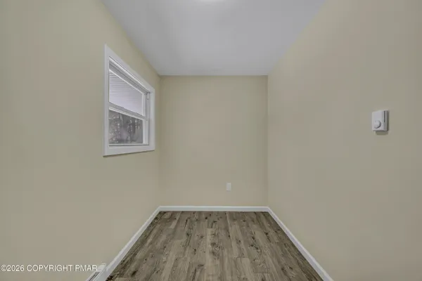 a view of an empty room with wooden floor and a window